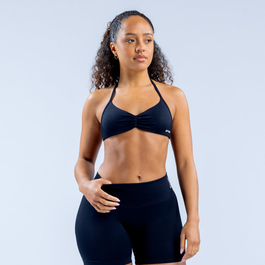 Strappy sports bra with knotted front, dark fabric, thin adjustable straps.