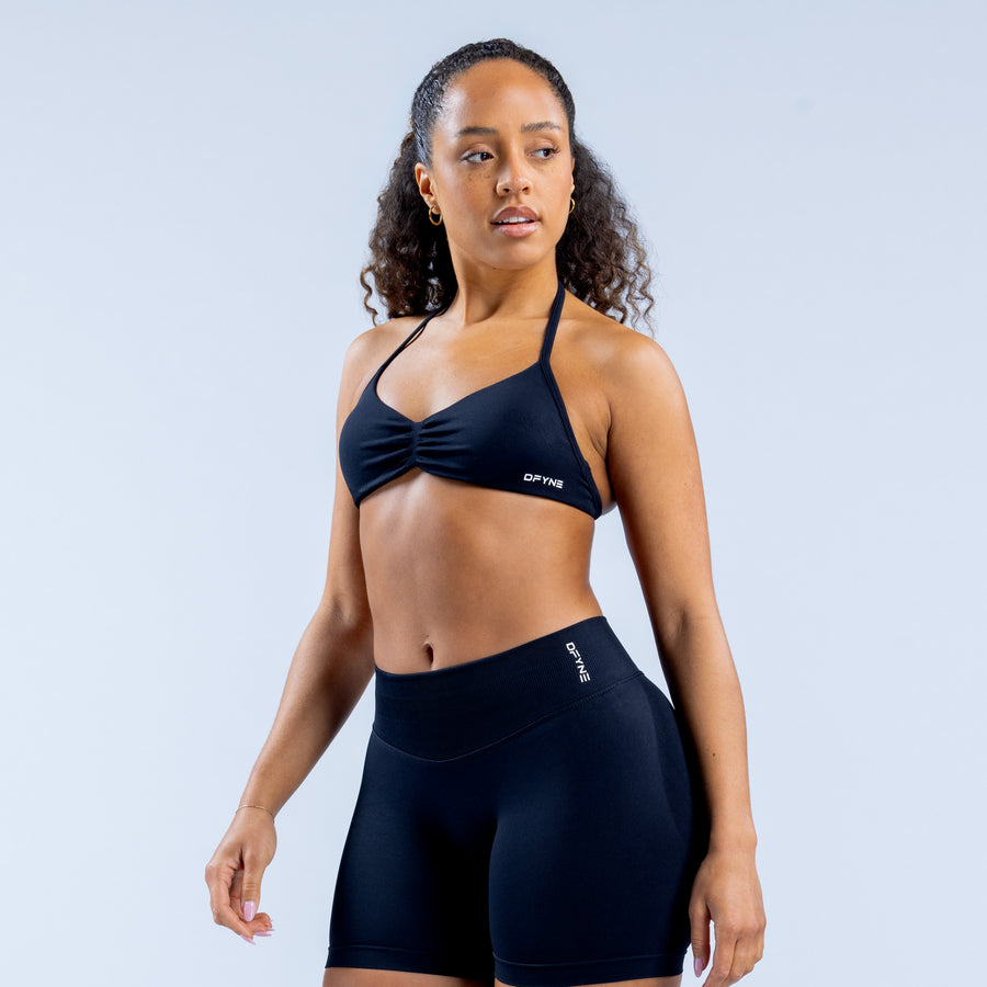 Strappy sports bra with thin halter straps and knotted front, dark fabric.