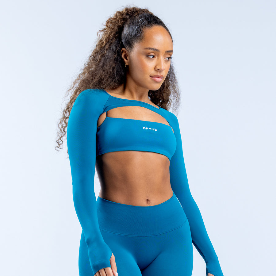 Teal long sleeve shrug with logo detail at chest and cropped length