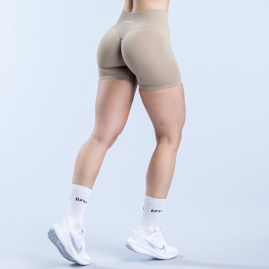 Beige athletic shorts, back view, fitted mid-thigh hem and smooth fabric