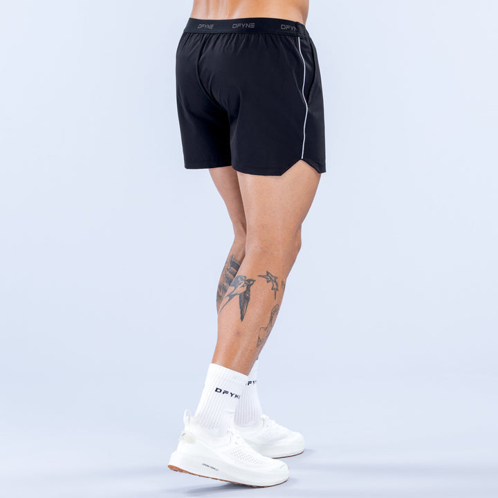 Men's black 4-inch training shorts, back view, elastic waistband and side piping