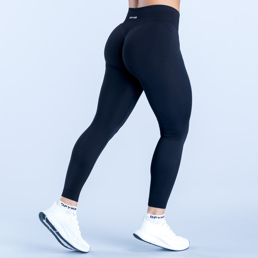 Black Defy leggings with high waistband and tapered legs, rear three-quarter view