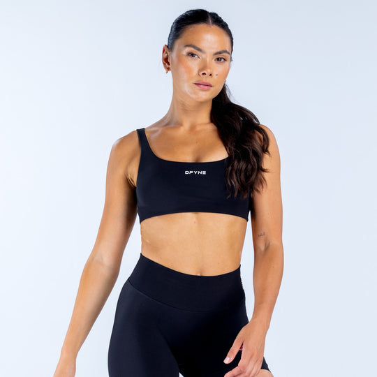 Black scoop-back sports bra with scoop neckline and DPYNE logo front.