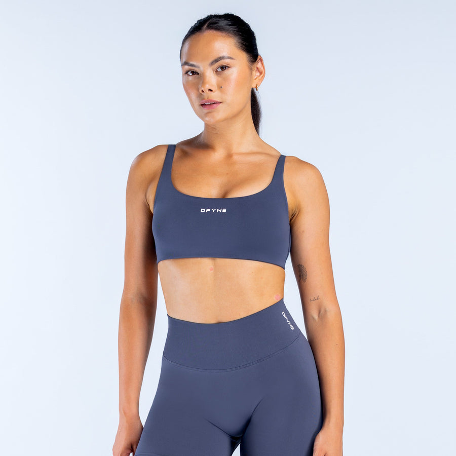 Scoop-back sports bra in dark navy, racerback straps and minimal logo front