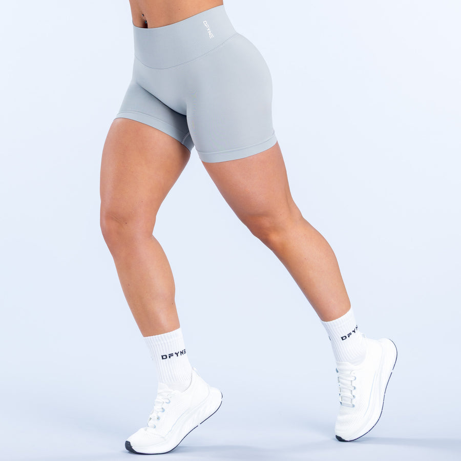 Light blue-gray athletic shorts, mid-thigh length, smooth stretch fabric.