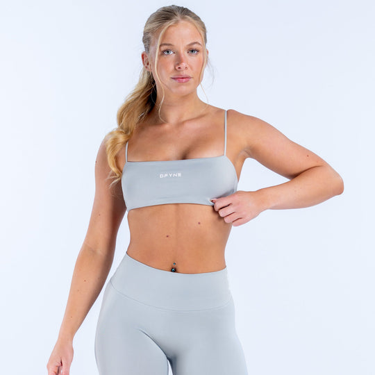 Light blue strappy sports bra with thin straps, cropped band, and small logo