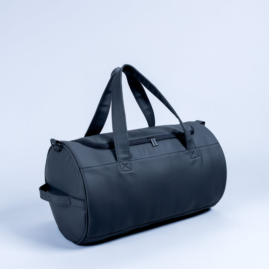 Duffle bag in dark blue with top handles, front pocket and shoulder strap.