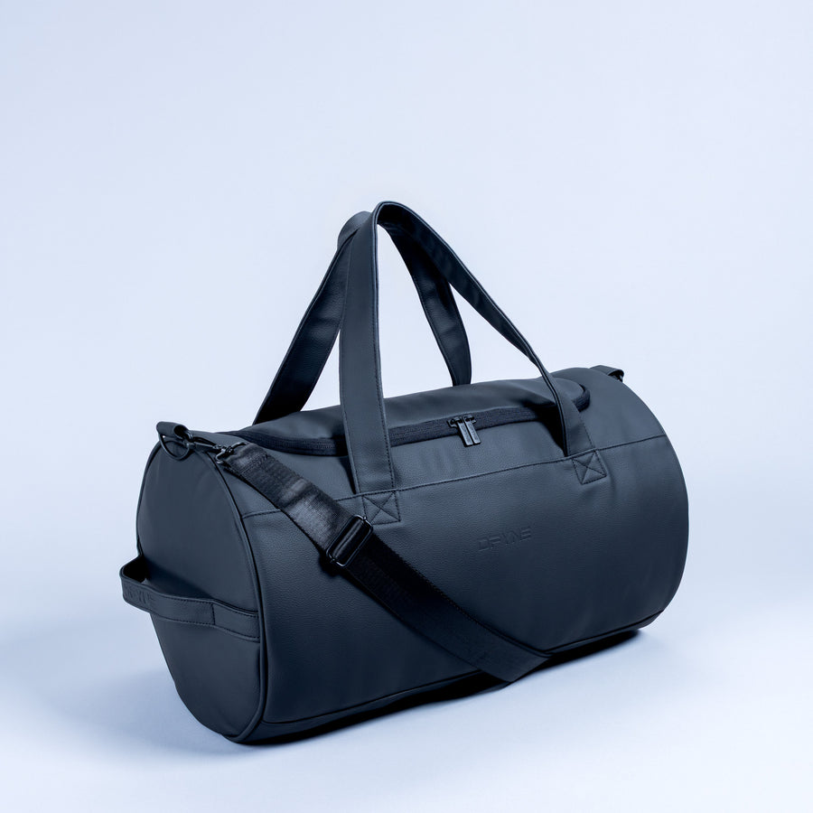 Duffle bag in dark blue with crossbody shoulder strap and top carry handles.