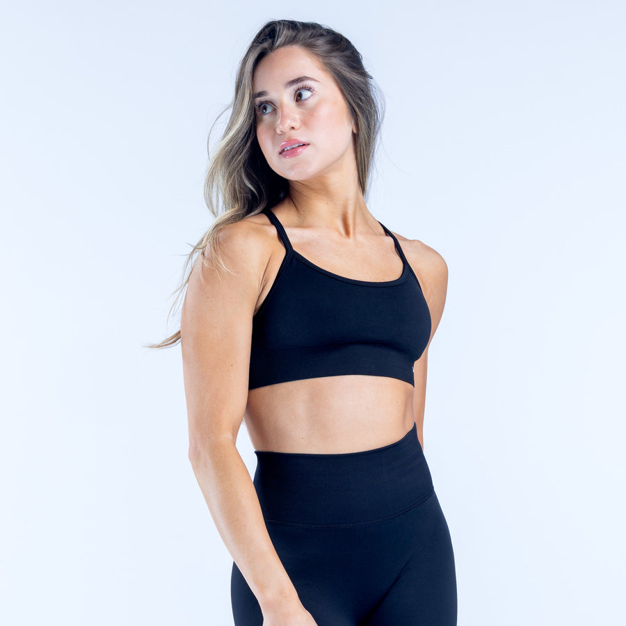 Black backless sports bra with narrow straps and smooth stretch fabric, front view