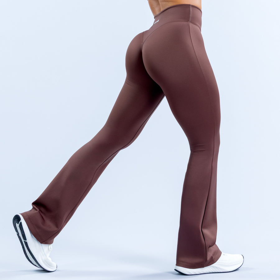 Women's dark mauve flared leggings, back view with curved hip seam and wide hem