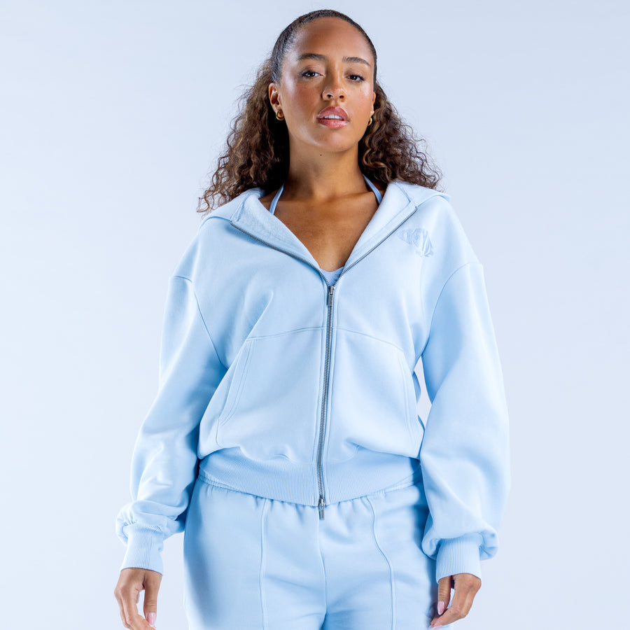 Light blue zip-up hoodie with hood, front zipper, and small chest logo
