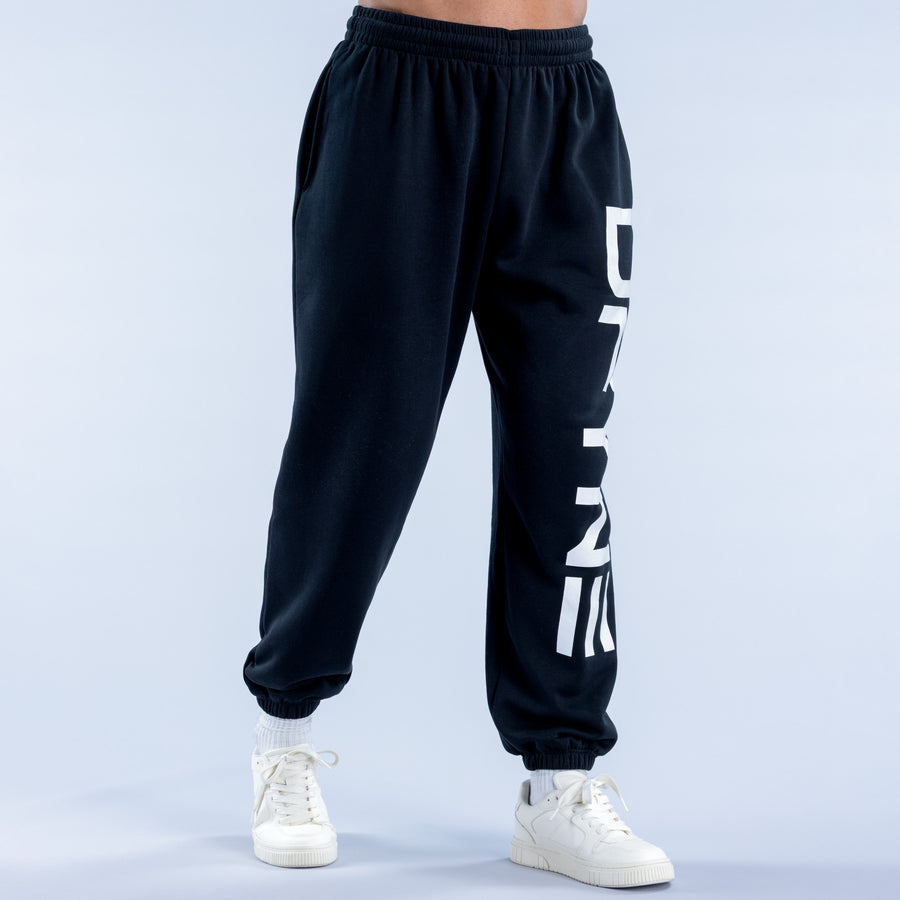Black cuffed jogger pants with white vertical logo on leg; elastic ankle cuffs