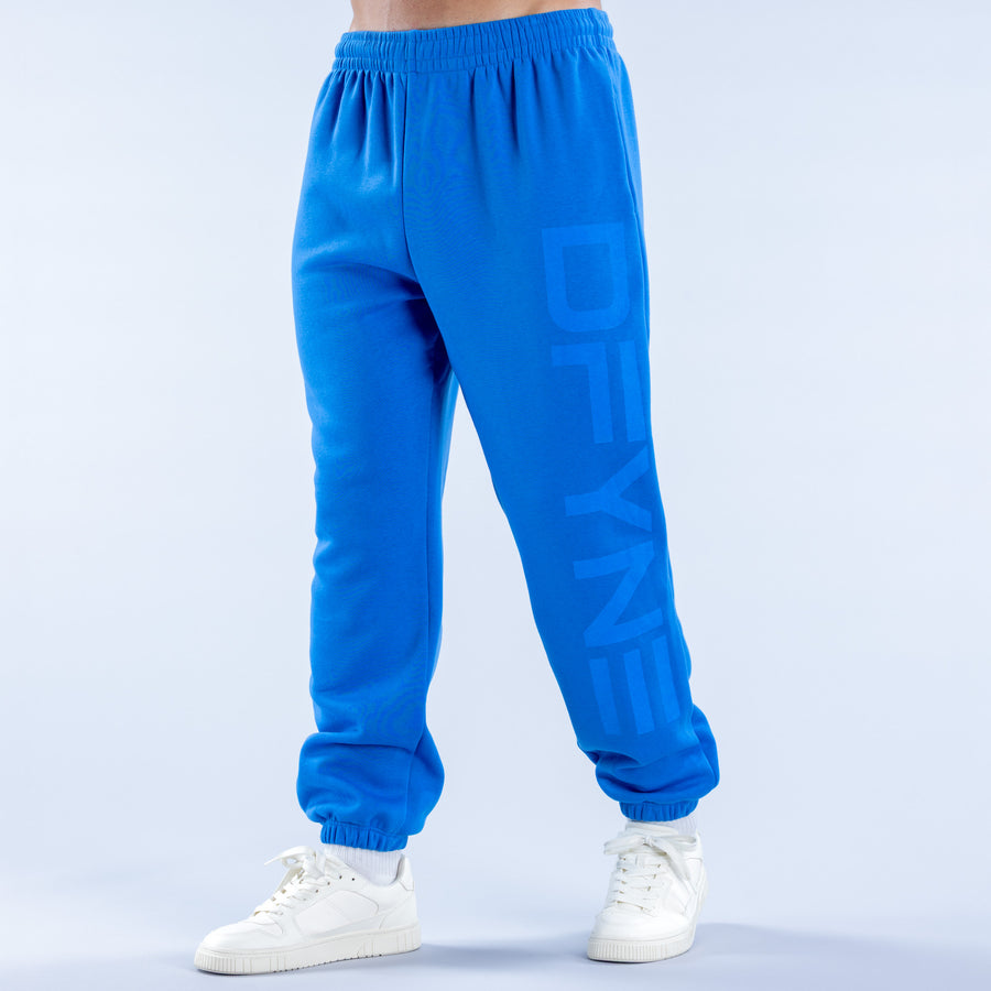 Blue cuffed jogger pants with elastic waistband and printed logo on the leg.