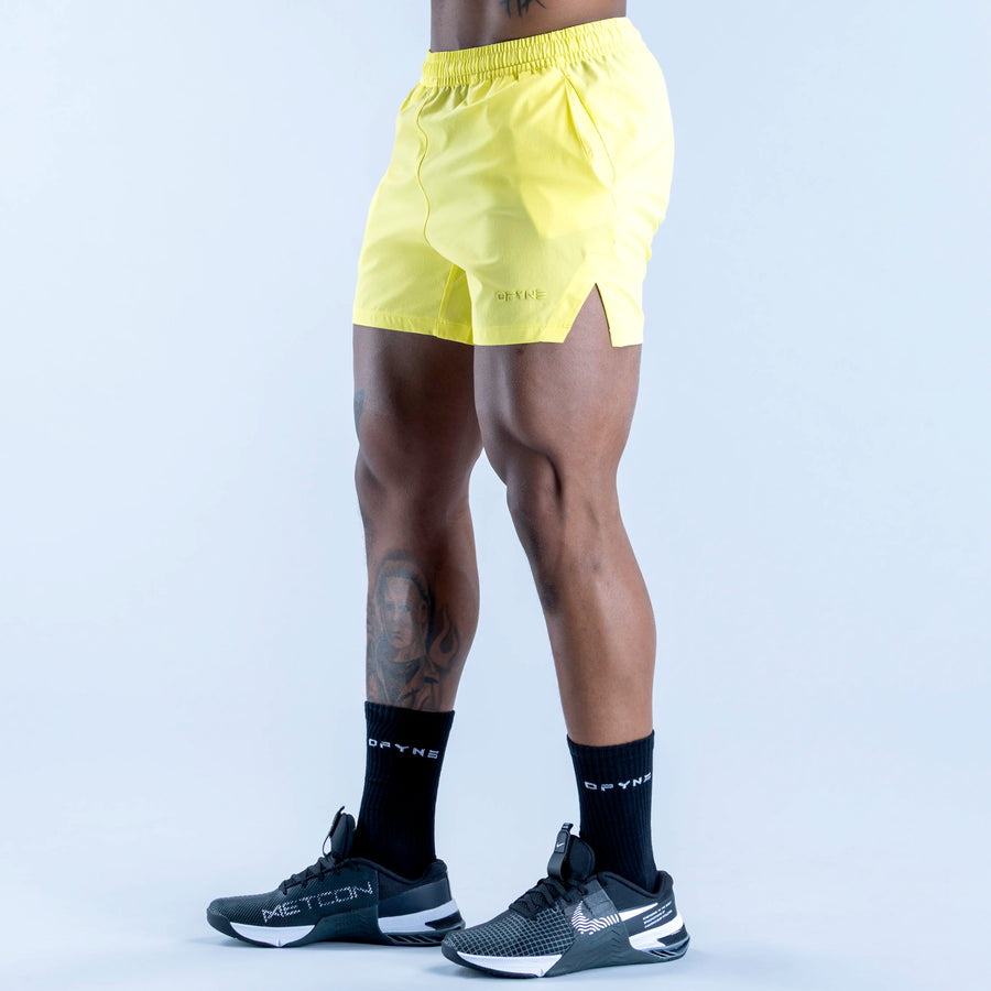 Lime yellow training shorts, side view, elastic waistband and mid-thigh length