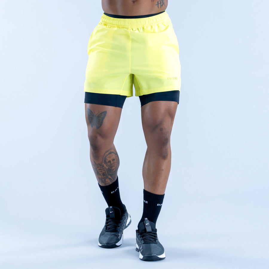 Neon yellow compression baselayer shorts, mid-thigh, elastic waistband, dark logo