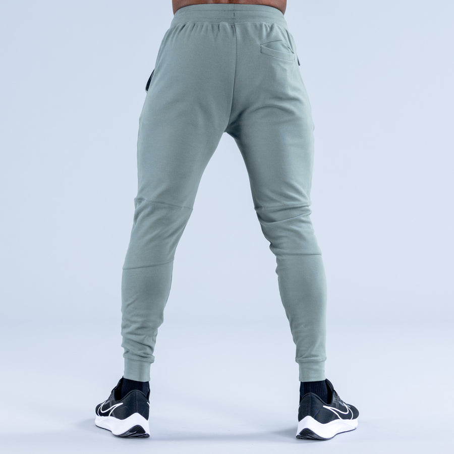 Sage green tapered jogger pants from back with side pockets and elastic cuffs