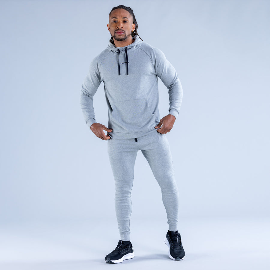 Light gray pullover hoodie with hood and drawstrings, kangaroo pocket, worn with joggers.