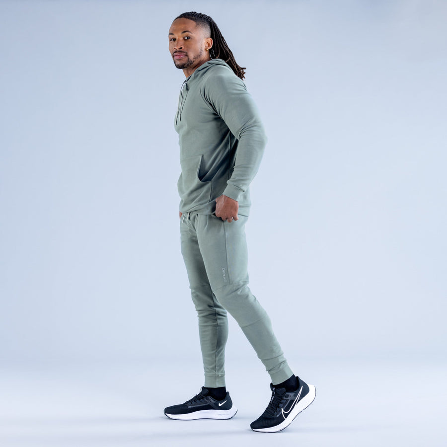Sage green midweight hoodie on model, side profile with drawstring hood