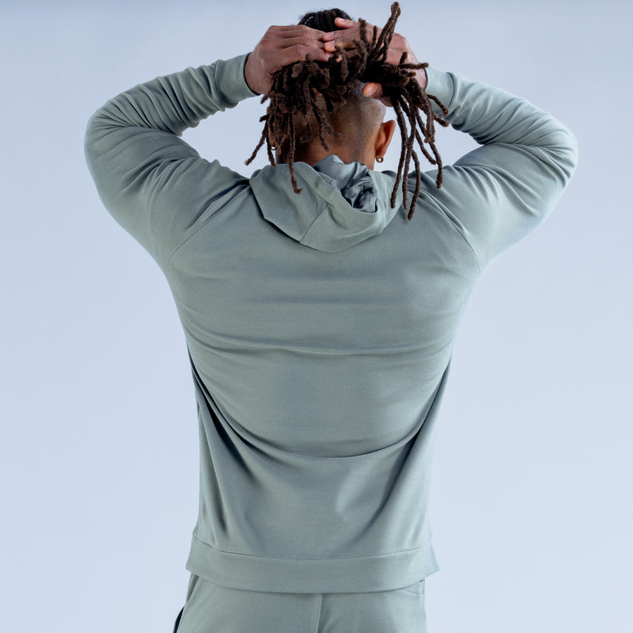 Sage green midweight hoodie on model, hooded back and drawstrings visible