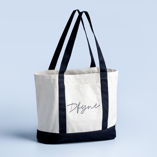 Canvas tote bag with dark straps, black bottom panel, and Dfyne script logo