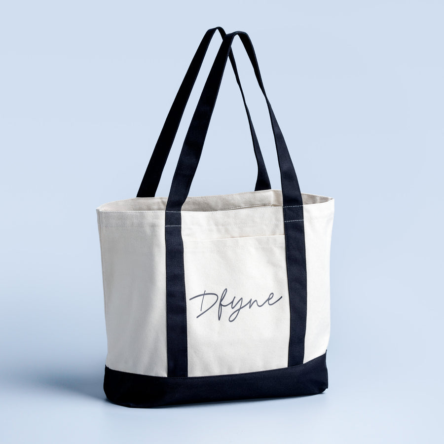 Canvas tote bag with dark straps, black bottom panel, and Dfyne script logo