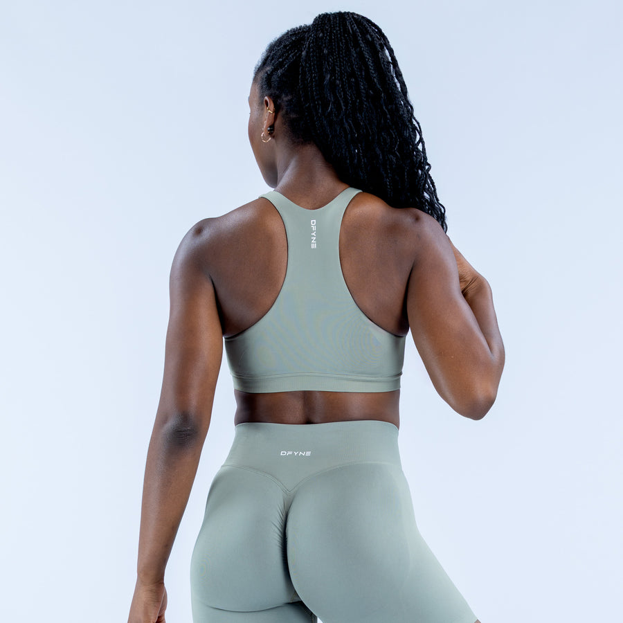Sage green racerback sports bra back view with central seam and cropped hem
