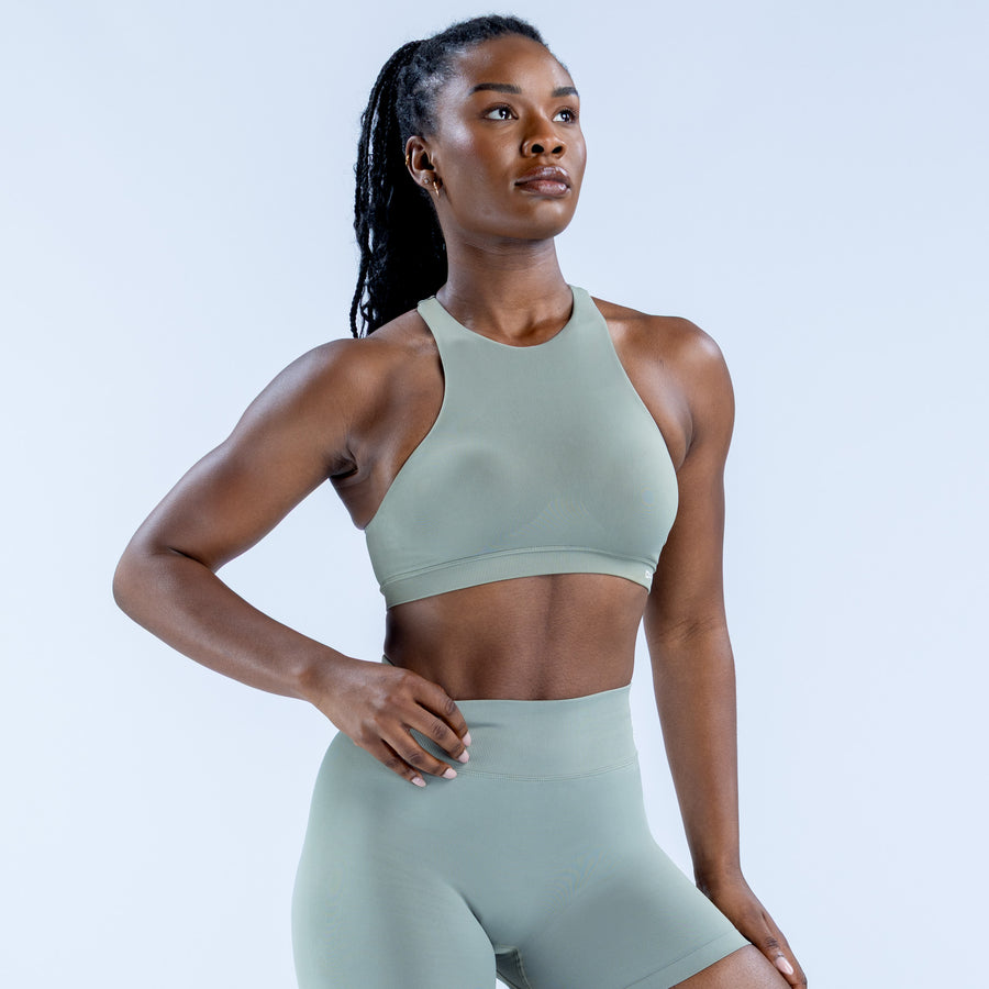 Sage green racerback sports bra with scoop front and supportive banded hem