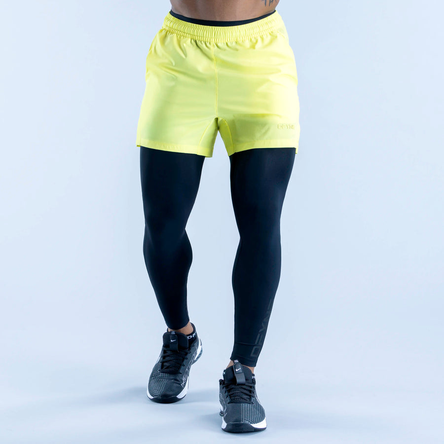 Unbound baselayer leggings in dark navy under neon yellow shorts overlay