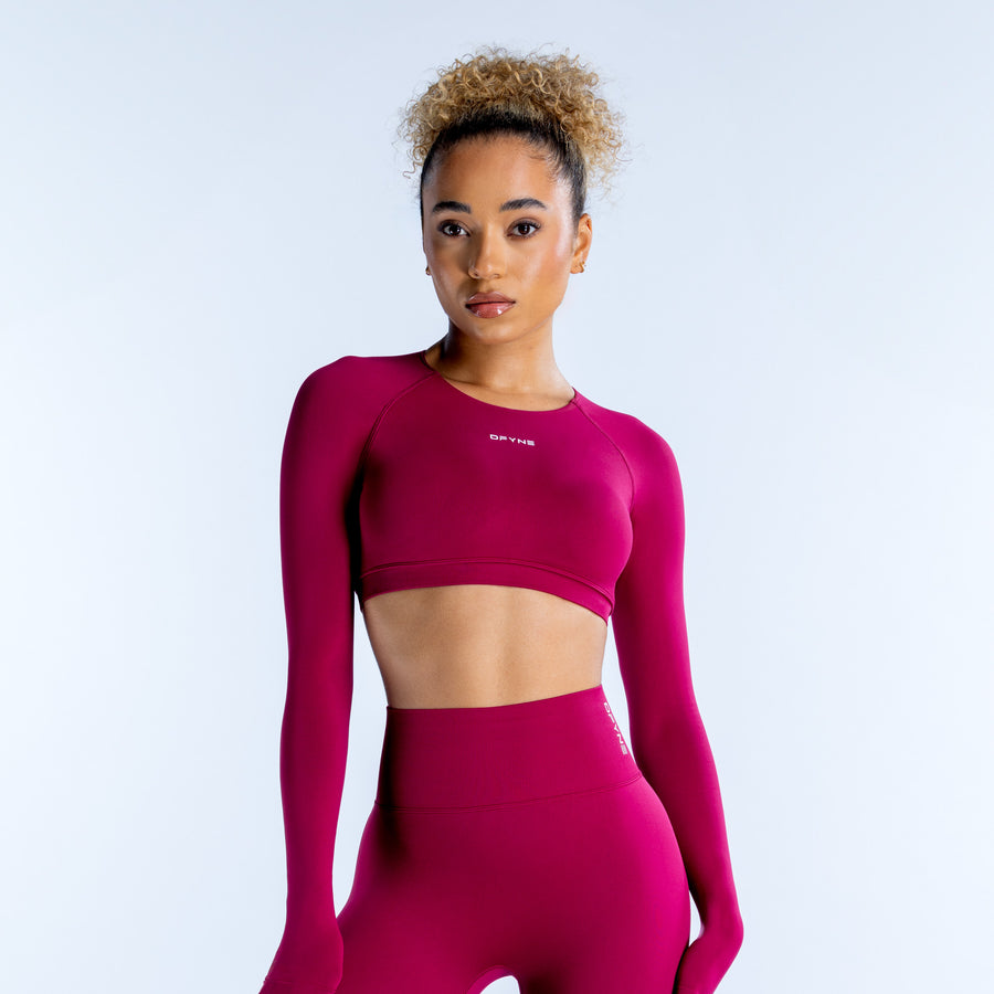 Magenta long-sleeve crop top with crew neck and small chest logo