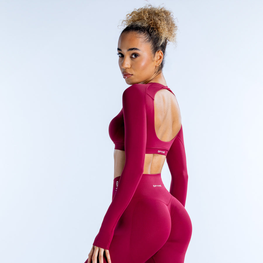 Magenta long-sleeve crop top with thumbholes and small chest logo