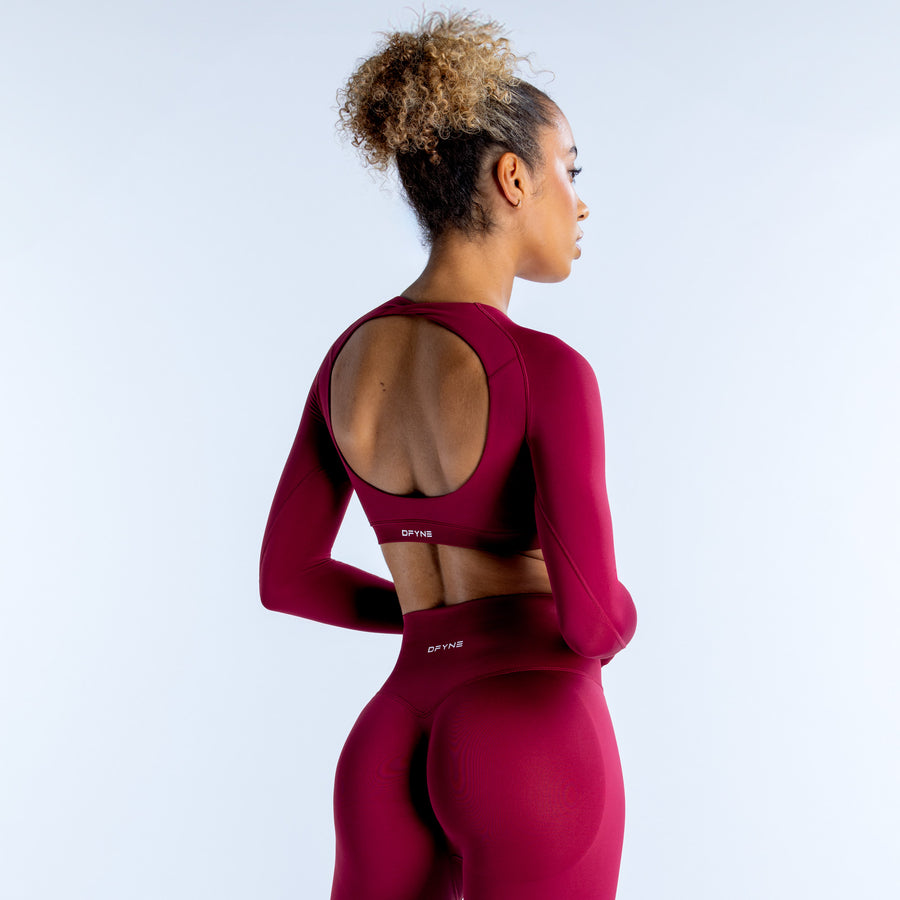 Magenta long-sleeve crop top with open back and small back logo