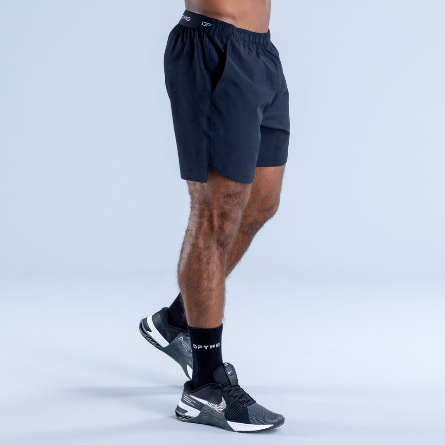 Training shorts, dark knee-length style with elastic waistband, side view.