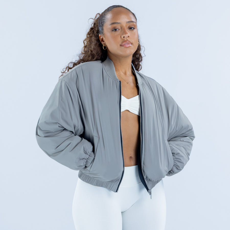 Gray bomber jacket with zip front and ribbed hem, worn open over a crop top