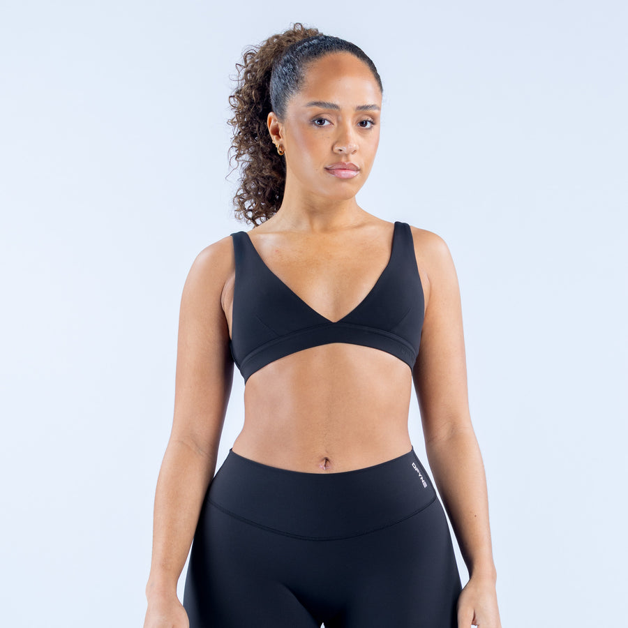 Origin minimal sports bra with V-neck and wide straps, seamless dark fabric.