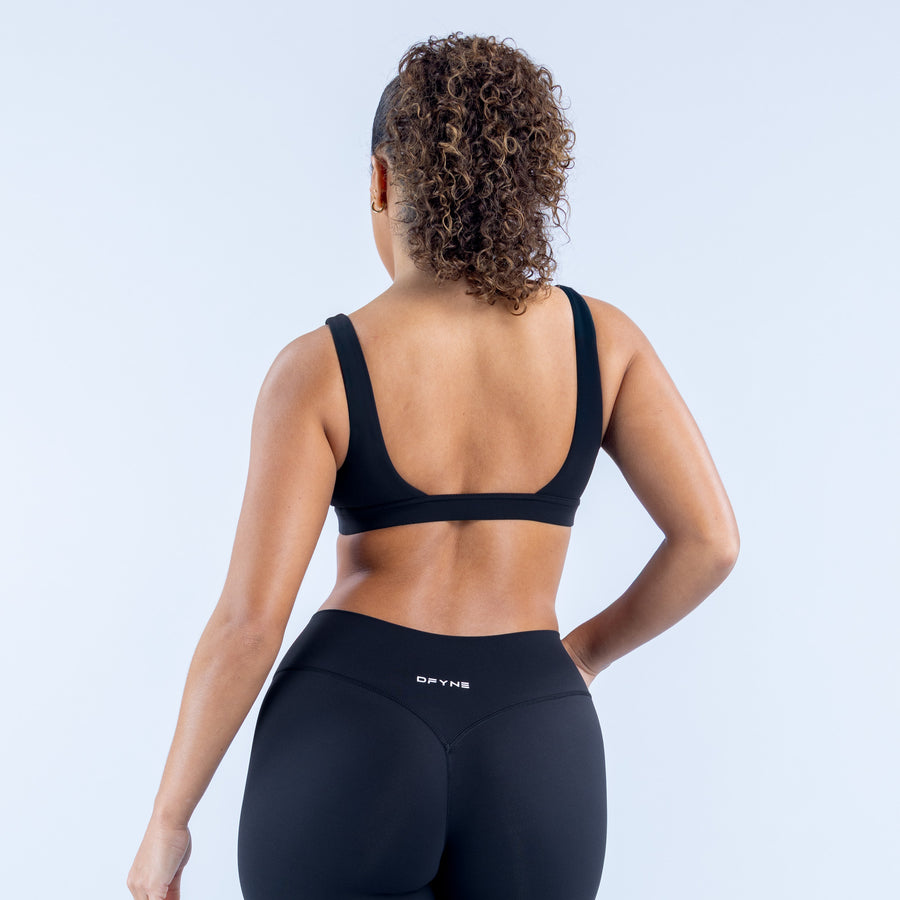 Minimal sports bra racerback with wide back straps and dark smooth fabric.