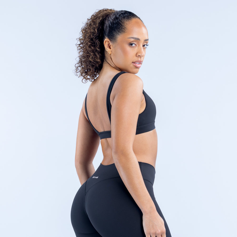 Minimal sports bra back view with wide straps and seamless dark fabric panel.