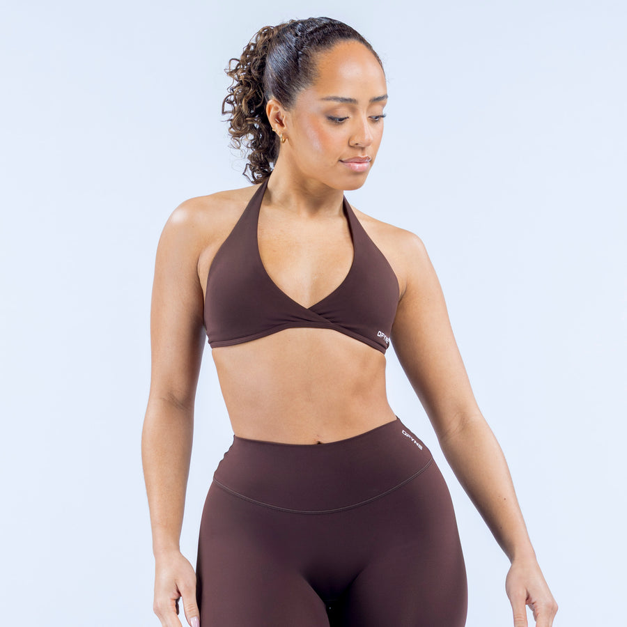 Origin halter bra front view, V-neck halter style with logo patch, dark brown