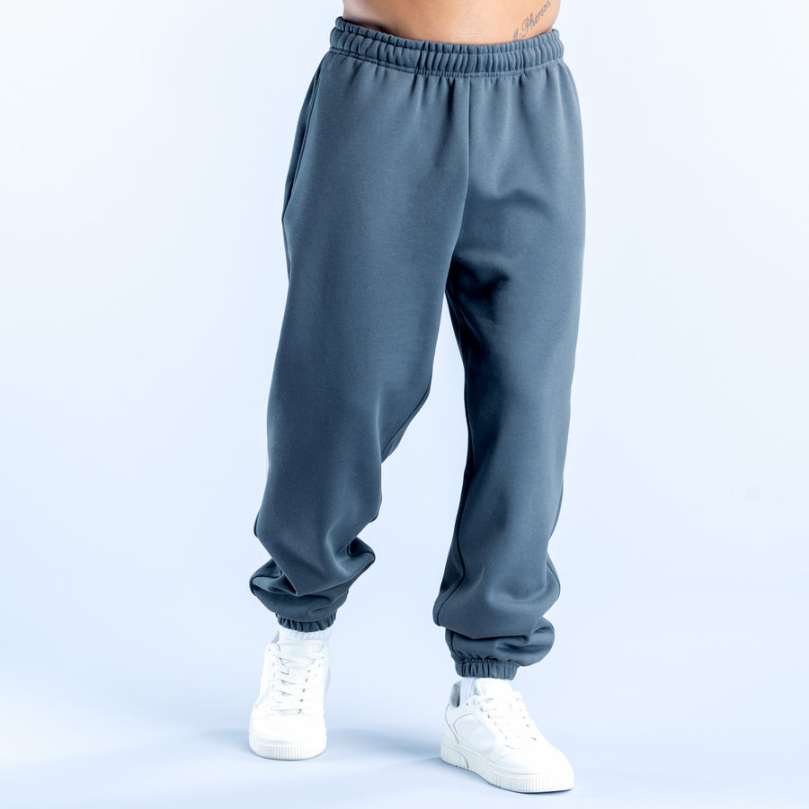 Dark teal jogger pants with elastic waistband, relaxed tapered legs, cuffed hems