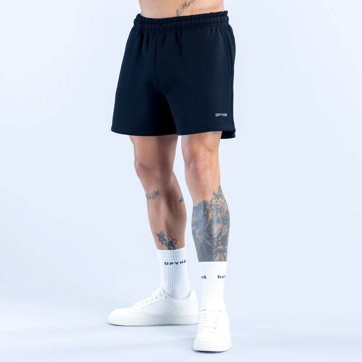 Dark athletic shorts with elastic waistband and small side logo, knee-length.