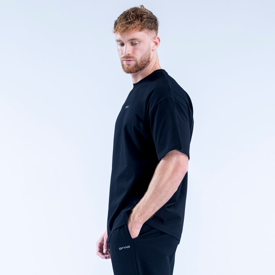 Black crew-neck T-shirt with small chest logo, short sleeves, side view.