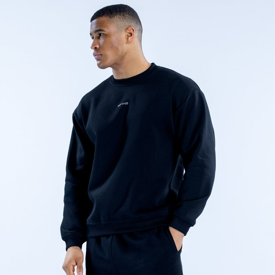 Black crewneck sweatshirt with chest logo, side view; ribbed cuffs and hem