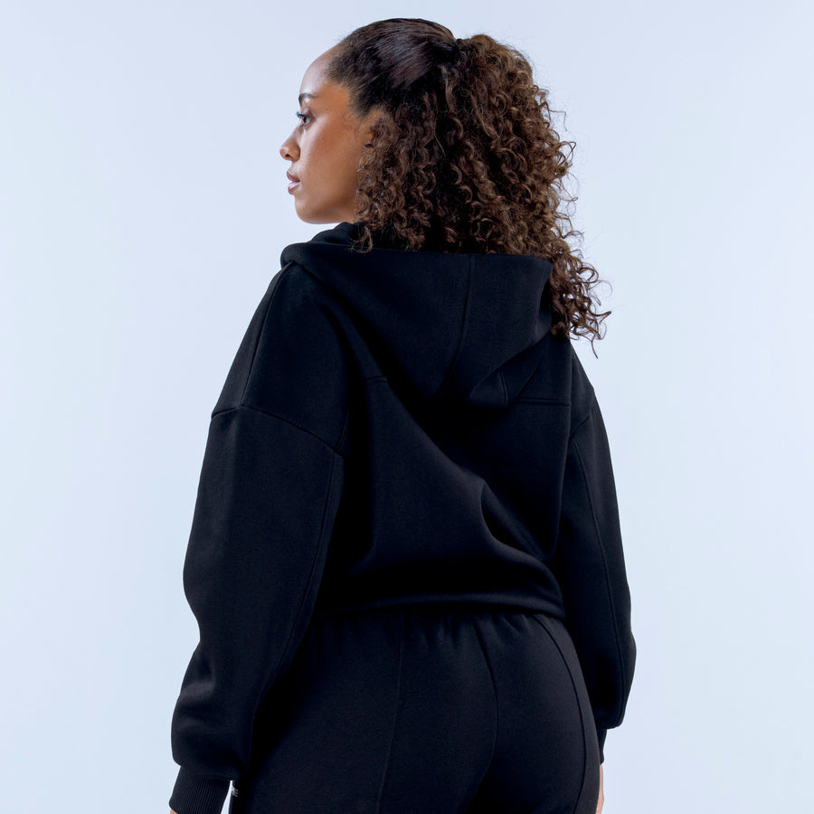 Dark zip-up hoodie with attached hood and pocket detail, back side view