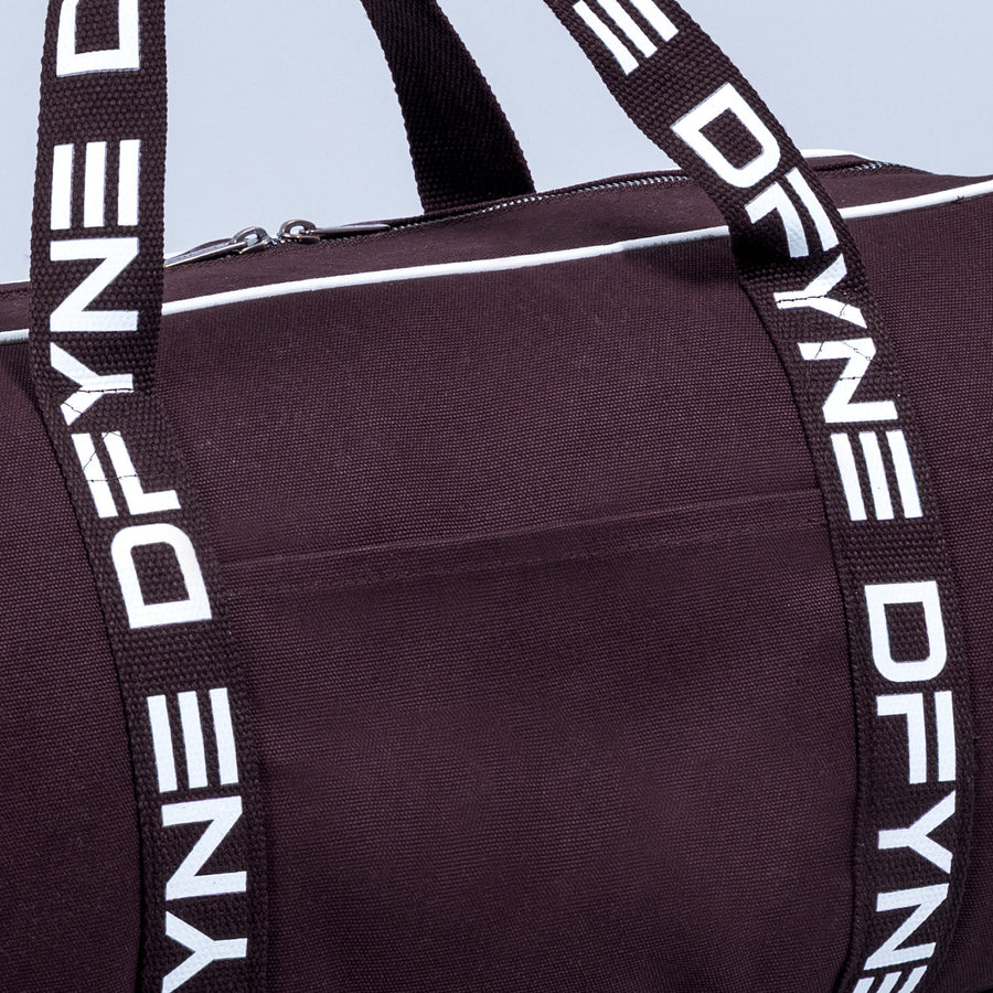 Burgundy duffle bag with white logo webbing shoulder strap and metal zipper