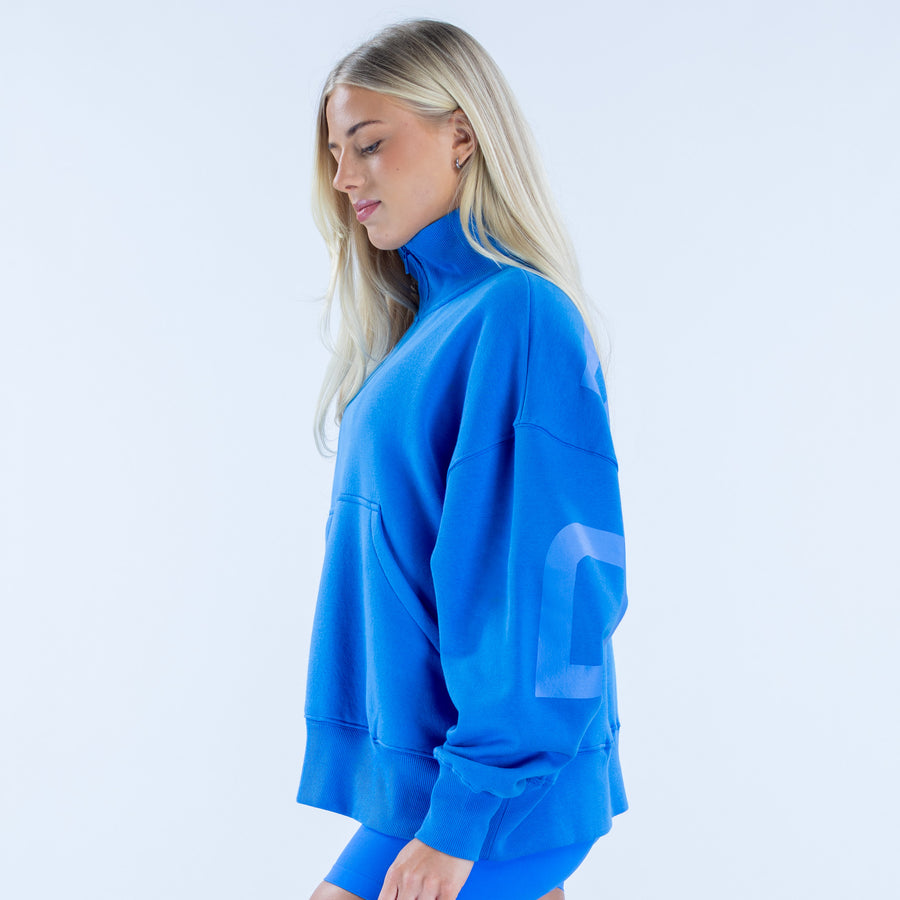Quarter-zip sweatshirt in bright blue with side profile; kangaroo pocket and cuffs