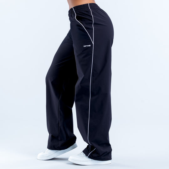 Black track pants with white piping stripe and elastic waistband, side view
