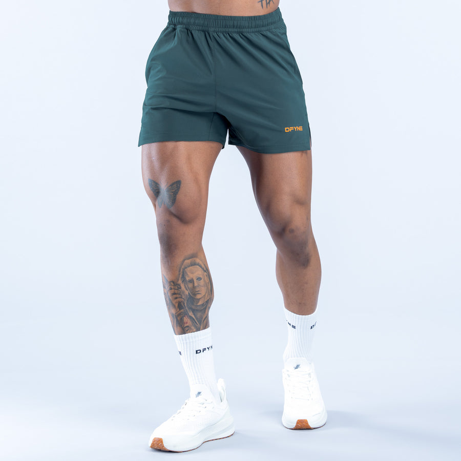 Dark green training shorts with elastic waistband, side logo, short length