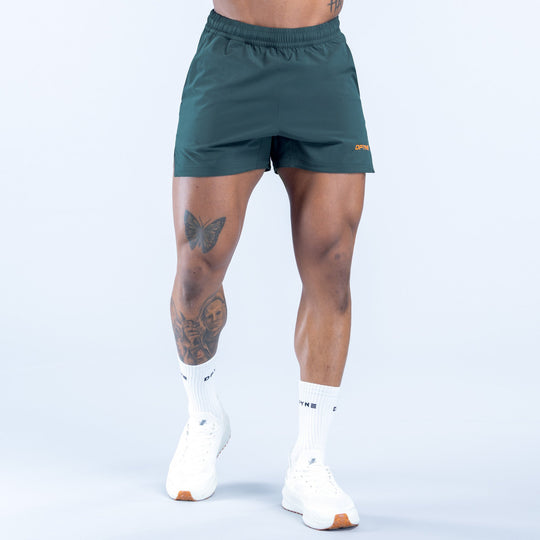 Men's teal training shorts with small orange logo near hem, elastic waist