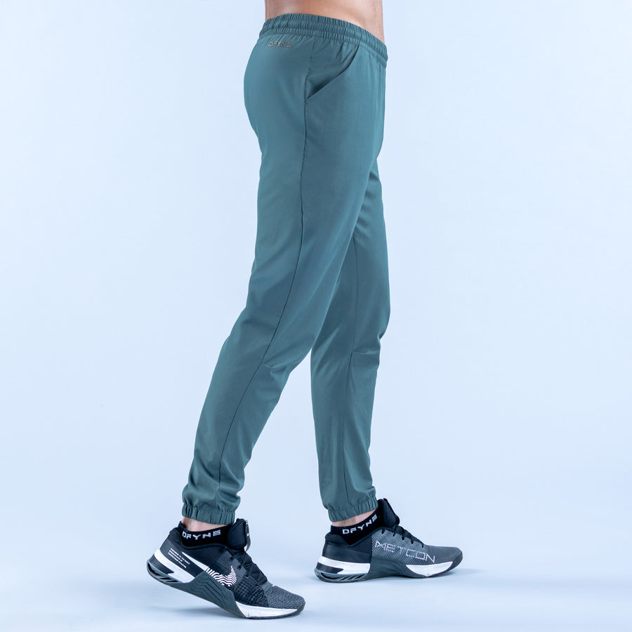 Teal training jogger pants from side view with elastic waistband and cuffed hems