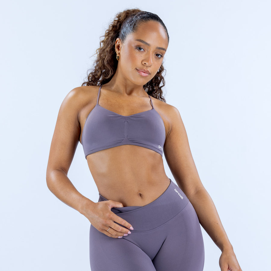 Women's purple racerback sports bra with front seam and small chest logo