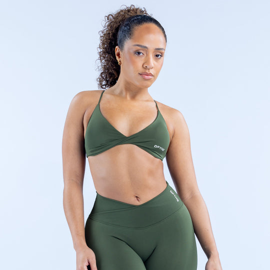 Green twist-front sports bra with racerback straps and DPYNE logo.